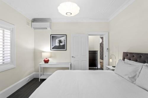 ein weißes Schlafzimmer mit einem großen Bett und einem Fenster in der Unterkunft Comfy 2-Bed Apartment with AC throughout in Sydney