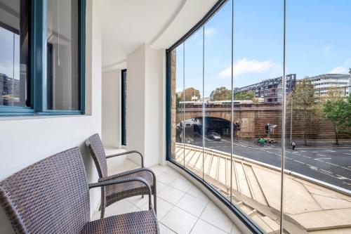 a balcony with two chairs and a view of a street at Oaks Sydney Castlereagh Suites in Sydney