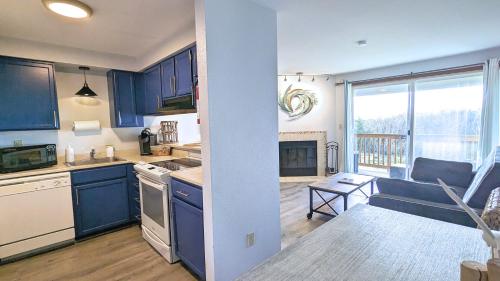 a kitchen with blue cabinets and a living room at Calypso at Nautilus - Pet Friendly, Walk to beach! in Ocean Shores