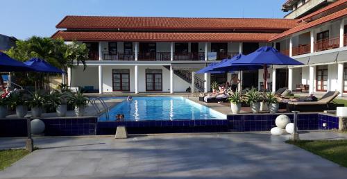 a swimming pool with blue umbrellas and a building at IMAGINE Villa Hotel in Mirissa