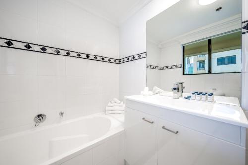 a white bathroom with a tub and a sink at Oaks Sydney Castlereagh Suites in Sydney