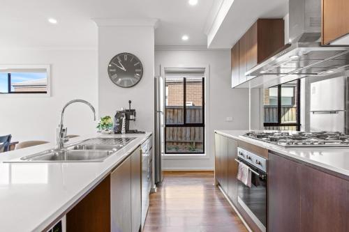 a kitchen with a sink and a clock on the wall at Point Cook's Spacious and Comfy 4BR/3BA Haven! in Point Cook