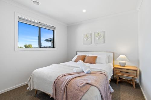 a white bedroom with a bed and a window at Point Cook's Spacious and Comfy 4BR/3BA Haven! in Point Cook