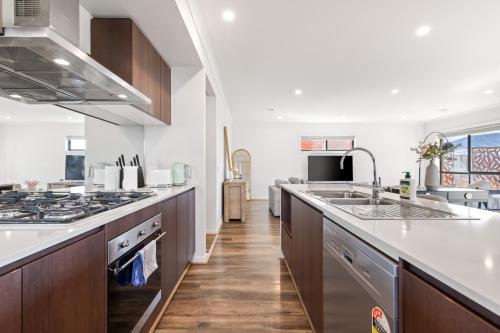 a large kitchen with a sink and a stove at Point Cook's Spacious and Comfy 4BR/3BA Haven! in Point Cook