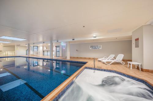 - une grande piscine avec 2 chaises dans une chambre dans l'établissement Oaks Sydney Castlereagh Suites, à Sydney