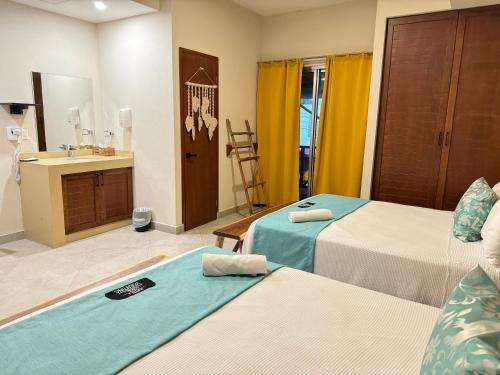 a hotel room with two beds and a sink at Suites Valentina in Puerto Morelos