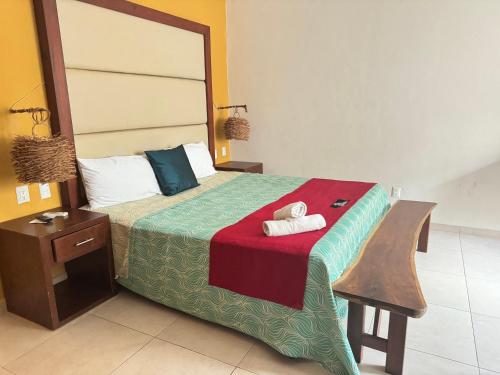 a bedroom with a bed with a red and green bedspread at Suites Valentina in Puerto Morelos