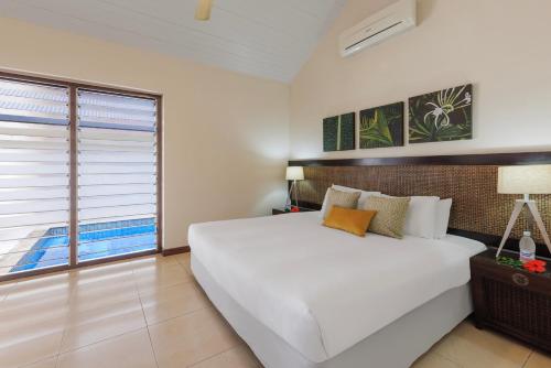 a bedroom with a large white bed and a window at Mangoes Resort in Port Vila