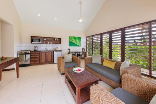 ein Wohnzimmer mit Sofas und einem Tisch sowie eine Küche in der Unterkunft Mangoes Resort in Port Vila