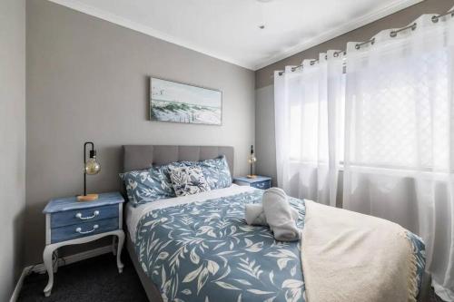 a bedroom with a bed with a blue and white bedspread at NEW! Breezy, Stylish 3BR Southport Oasis! in Gold Coast