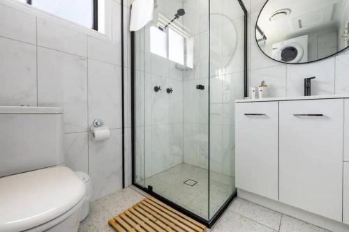 a bathroom with a shower and a toilet and a mirror at NEW! Breezy, Stylish 3BR Southport Oasis! in Gold Coast
