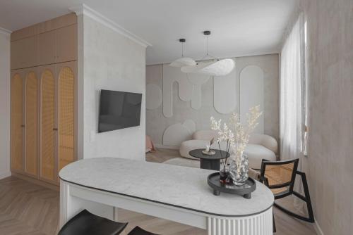 a white living room with a table and a tv at Danės23 - CANDY studio, Self Check-in, Free Parking, Park and River View, Oldtown, A/C in Klaipėda
