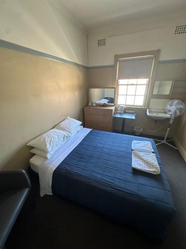 a bedroom with a bed with a blue comforter and a window at Coffs Harbour Hotel in Coffs Harbour