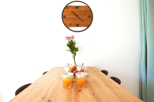 une table avec deux verres de jus d'orange et une horloge dans l'établissement Appartement Fantino - Welkeys, à Palavas-les-Flots
