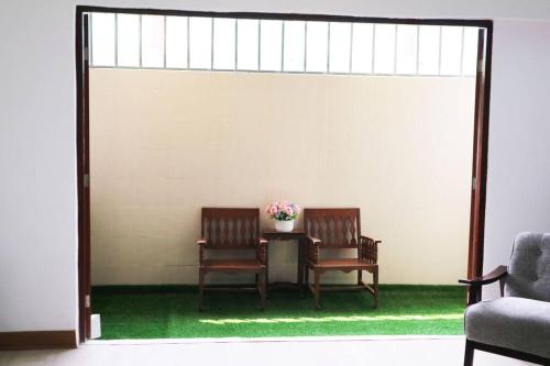 two chairs and a table with a vase of flowers at Happyhouse Laksi station (PK14) in Lak Si