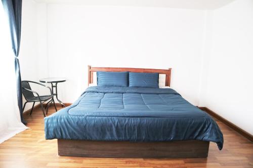 a bedroom with a bed with blue sheets and a table at Happyhouse Laksi station (PK14) in Lak Si