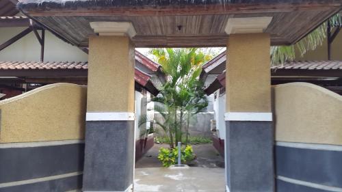 a building with columns and a palm tree in the courtyard at Trawangan Cottages in Gili Trawangan