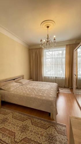 1 dormitorio con cama y lámpara de araña en Salamat Apartments - Best location 8, en Bishkek