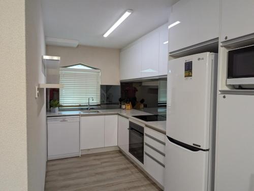 cocina con armarios blancos y nevera blanca en Byron Bay Beachfront Apartments, en Byron Bay