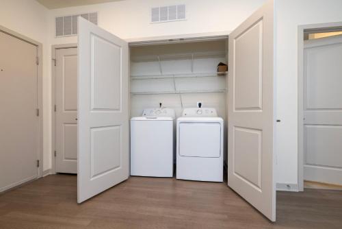 two white refrigerators in a room with two doors at TWO Modern Nulu CozySuites in Louisville