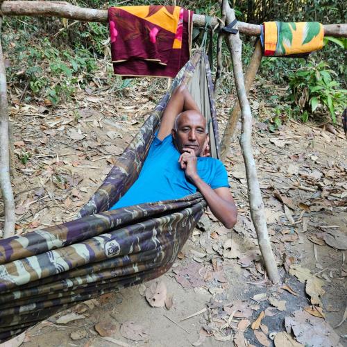 a man laying in a hammock under a tree at Banlung Mountain View Treks & Tours in Banlung