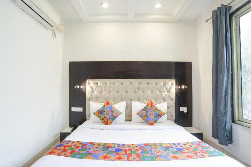 a bedroom with a large white bed with colorful pillows at FabHotel Madhuban Inn in Rishīkesh