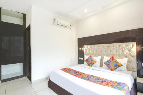 a bedroom with a large white bed with colorful pillows at FabHotel Madhuban Inn in Rishīkesh