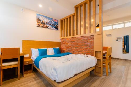a bedroom with a bed and a desk and a brick wall at POKHARA APARTMENTS INN in Pokhara