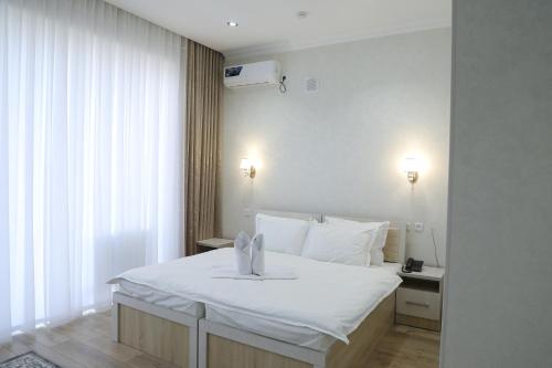 1 dormitorio con cama blanca y ventana en Status Hotel, en Qarshi