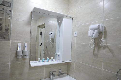 y baño con ducha, espejo y lavamanos. en Status Hotel, en Qarshi