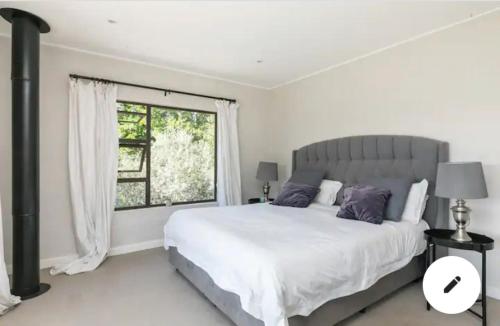 a white bedroom with a large bed and a window at The Urban Farmhouse: Find Peace&Rest@the Farmhouse in Chartwell