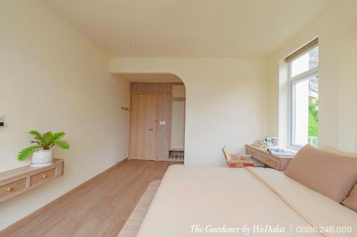 a bedroom with a large white bed and a window at The Gardener by WeDalat in Da Lat