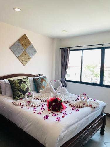 a bed with two swans and flowers on it at The Guest Hotel & Hostel in Chiang Mai