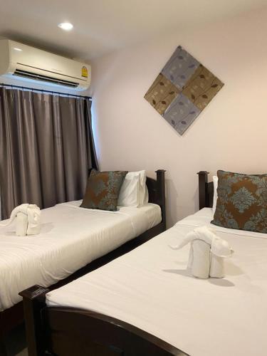 two beds in a hotel room with white sheets at The Guest Hotel & Hostel in Chiang Mai