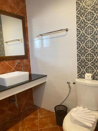 a bathroom with a toilet and a sink and a mirror at The Guest Hotel & Hostel in Chiang Mai
