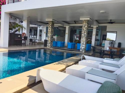 a swimming pool with white chairs and a table at Manarra Sea View Resort in Puerto Galera