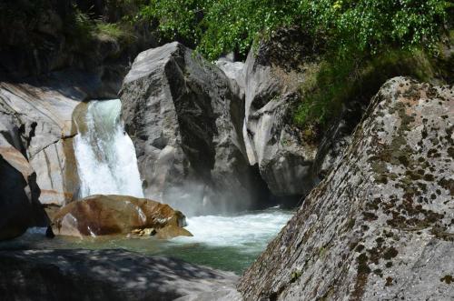 a bear in the water next to a waterfall at Kudrat - A Boutique Homestay- Tirthan Valley in Banjār