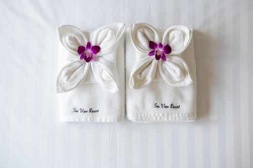 two white towels with purple flowers on them at SeeView Resort (ซีวิว รีสอร์ต) in Ban Pak Nam