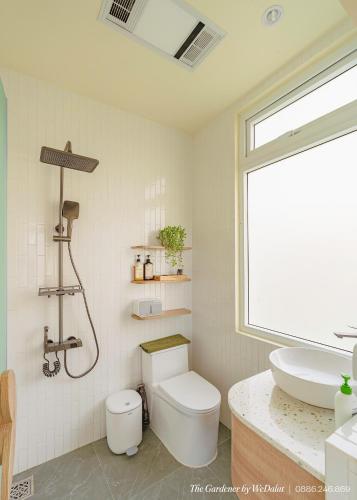 a white bathroom with a toilet and a sink at The Gardener by WeDalat in Da Lat