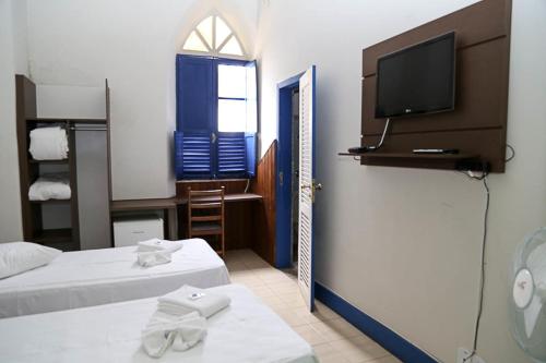 a room with two beds and a television on a wall at Hotel Providencia in Mariana