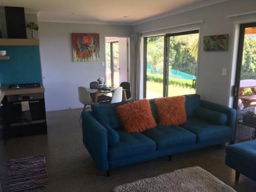 a living room with a blue couch and a table at Kaimai Range Country Getaway in Katikati