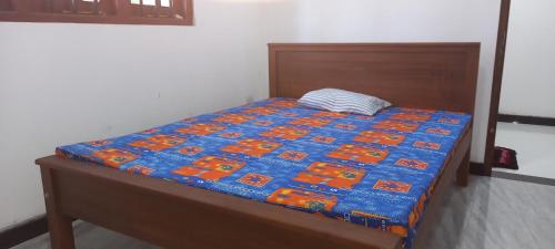 a bed with a blue and orange quilt on it at Family Villa Thalpavila in Ambatenna