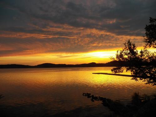 een zonsondergang boven een grote hoeveelheid water bij Ungurmalas Mazā māja in Auciems