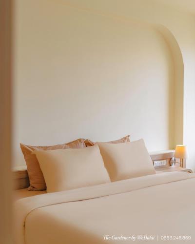 a white bed with pillows on top of it at The Gardener by WeDalat in Da Lat