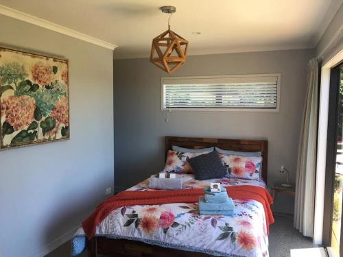 a bedroom with a bed with a red blanket at Kaimai Range Country Getaway in Katikati