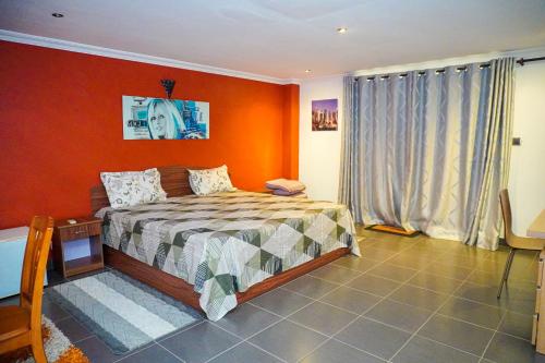 a bedroom with a bed with an orange wall at OTF Rooms & Apartments in Belle Mare