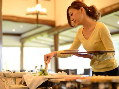a woman standing in a kitchen preparing food at Towada Prince Hotel in Kosaka