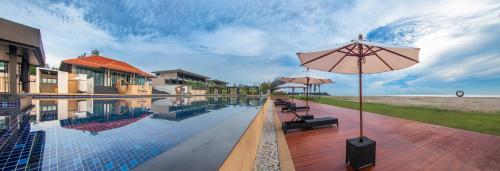 a pool with an umbrella next to a building at Sea Sand Sun Hua Hin by JC Kevin Hotel & Resort in Phetchaburi