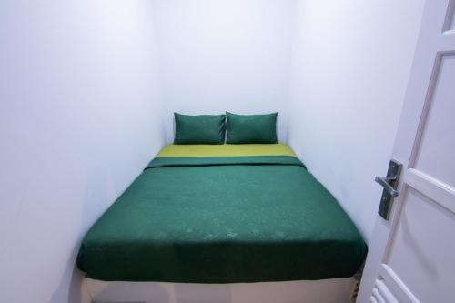 a bed in a white room with a green mattress at Kareem Syariah Hostel Bukittinggi in Bukittinggi
