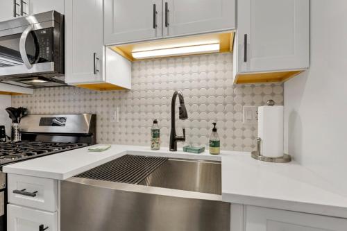 a kitchen with white cabinets and a stainless steel sink at The Worthington - 3 BR 2 5 Bath and Parking in Columbus